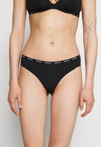 Black cotton bikini briefs with a logo waistband, featuring a smooth texture and low-rise design. No additional patterns or accents.