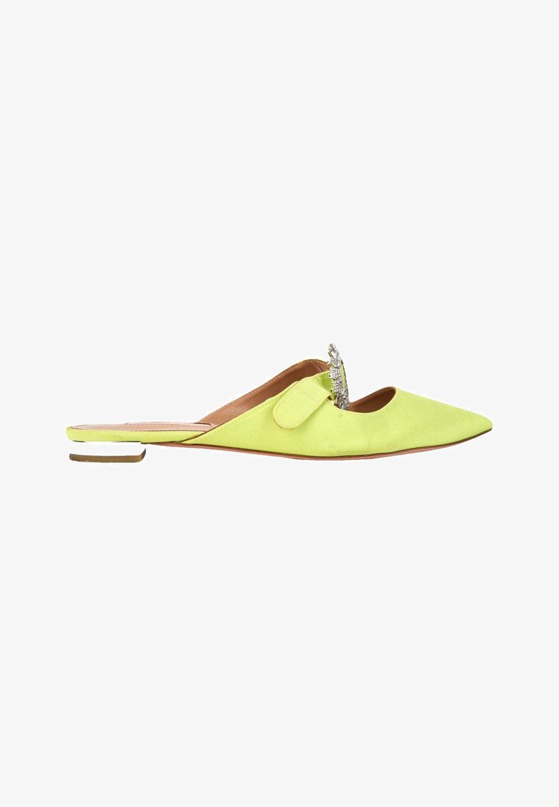 Chaussure plate jaune à bout pointu, modèle slip-on, avec un talon bas et une boucle décorative argentée sur le dessus.