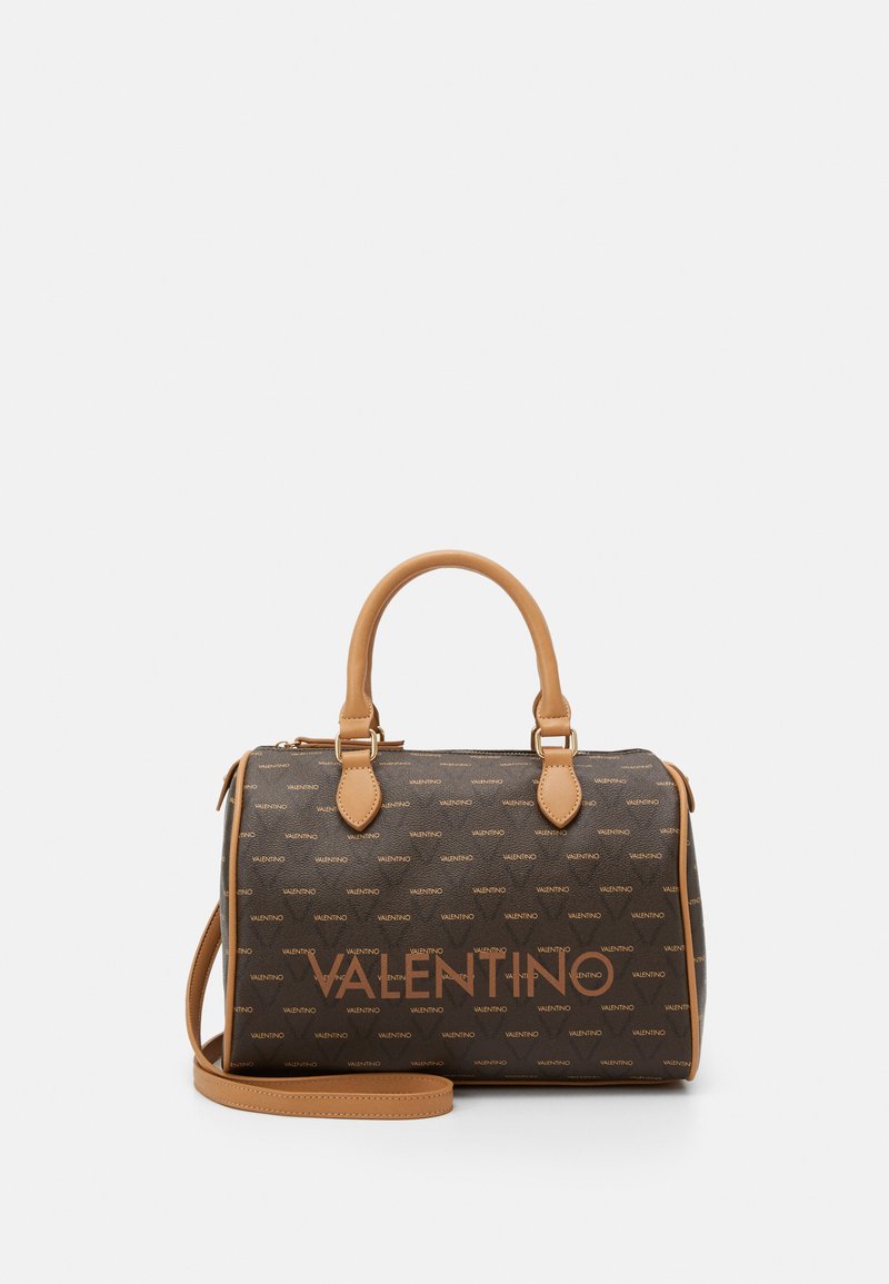 Brown patterned handbag with tan leather accents, features top handles, detachable shoulder strap, and embossed brand logo on front.