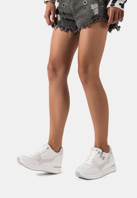 Sneaker bianche con un mix di tessuto liscio e testurizzato, caratterizzate da una suola spessa, design con lacci e sottili accenti grigi.