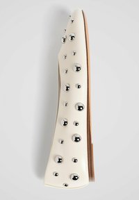 Hvide lædersko med flad sål, runde sølvnitter og lysebrune såler, set fra siden mod en lys baggrund.