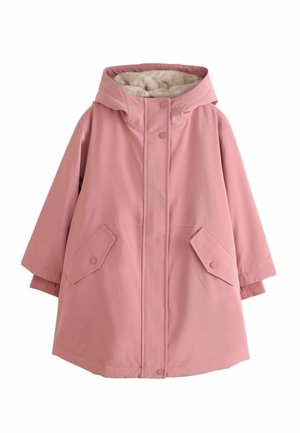 Person trägt eine rosa Jacke mit goldenen Druckknöpfen und Reißverschluss, zeigt eine Hand teilweise im Ärmel mit passendem rosa Bündchen.