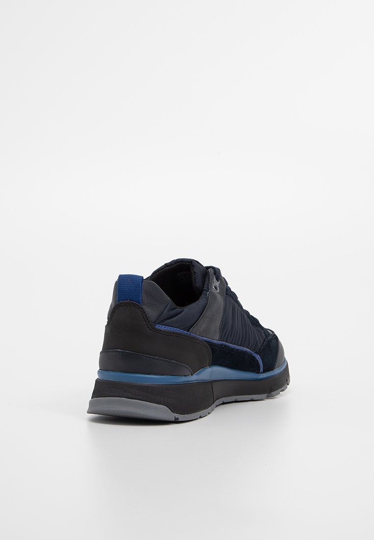 Męskie buty sportowe w granatowej skórze i zamszu. Charakteryzują się gładkimi i teksturowanymi panelami, niebieskim akcentem na pięcie oraz szarym gumowym podłożem.