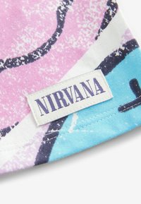 T-shirt en coton avec un design abstrait rose et bleu, portant une étiquette blanche avec le mot "NIRVANA" en lettres violettes en gras.