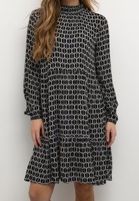 Abito nero a maniche lunghe con un motivo geometrico bianco e tonalità di blu, con scollatura arricciata e orlo arricciato.