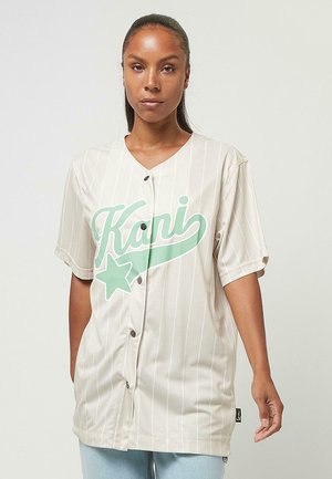 Beige gestreiftes Jersey mit V-Ausschnitt, großem grünen "Kani"-Text und Sternengrafik, kurzen Ärmeln und Knopfverschluss.