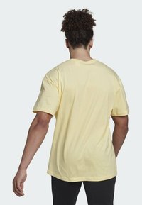 T-shirt di cotone giallo con scollatura rotonda e maniche corte. La parte posteriore presenta un design semplice, con una vestibilità comoda e orlo dritto.