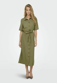 Khaki midi kleit lühikeste varrukatega, eesnupudega kinnitamine, seotud vöökoht, üks rinnatasku, küljetuuleaugud, valmistatud tekstuursest kangast.
