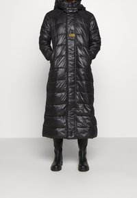Abrigo tipo puff negro con diseño largo, cuenta con capucha, textura brillante, patrón de acolchado horizontal y cierre delantero de cremallera.