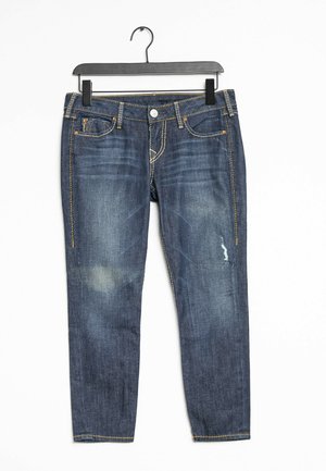 Donkerblauwe denim jeans met een slim fit, met voorzakken, versleten accenten en contrasterend gele stiksels. Hangt aan een zwarte hanger.