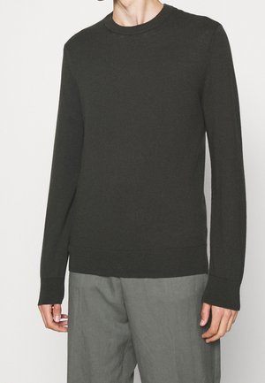 Maglione a maglia verde scuro con maniche lunghe, scollo rotondo e polsini e orlo a costine. Abbinato a pantaloni grigi, che presentano una vestibilità comoda.