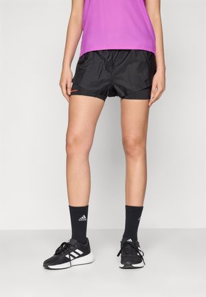 Sorte lette løpeshorts med en tettsittende innerforing, med oransje logo. Kombinert med svarte atletiske sokker og sko.