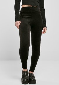Leggings noirs à côtes avec une taille haute, texture douce et design ajusté. Associés à des mocassins noirs chunky.