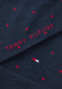 Calcetines de algodón azul marino con un patrón de puntos rojos y el texto bordado "TOMMY HILFIGER" en rojo, con un pequeño logotipo como acento.