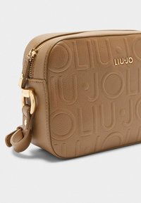 Borsa crossbody in finta pelle marrone con design del logo in rilievo, hardware dorato, chiusura con zip e tracolla rimovibile.