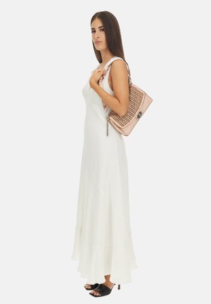 Abito maxi bianco, fluido, con orlo a balze; modella che tiene in mano una borsa rosa con un design perforato e dettagli in metallo argentato.