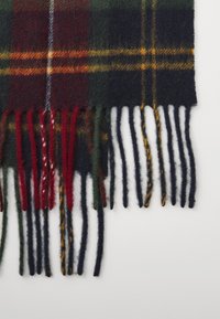 Sciarpa di lana con motivo tartan in verde, rosso, blu navy e giallo, con bordi sfrangiati. Finitura testurizzata con frange di lunghezze alternate.
