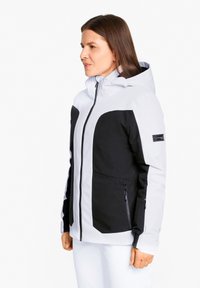 Damenjacke mit einem Design in Weiß und Schwarz, mit durchgehendem Reißverschluss, verstellbare Kapuze und strukturiertem Stoff für Wetterschutz.