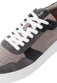 Sneaker din piele întoarsă și piele gri, cu șireturi albe, vârf perforat, accente negre și o talpă din cauciuc alb. Design cu vârf rotunjit.