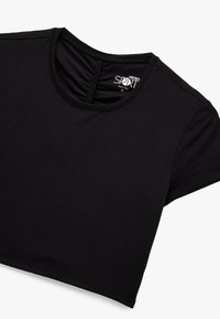 Camiseta deportiva negra corta, hecha de algodón suave, con cuello redondo y mangas cortas, y un detalle fruncido en la parte posterior.