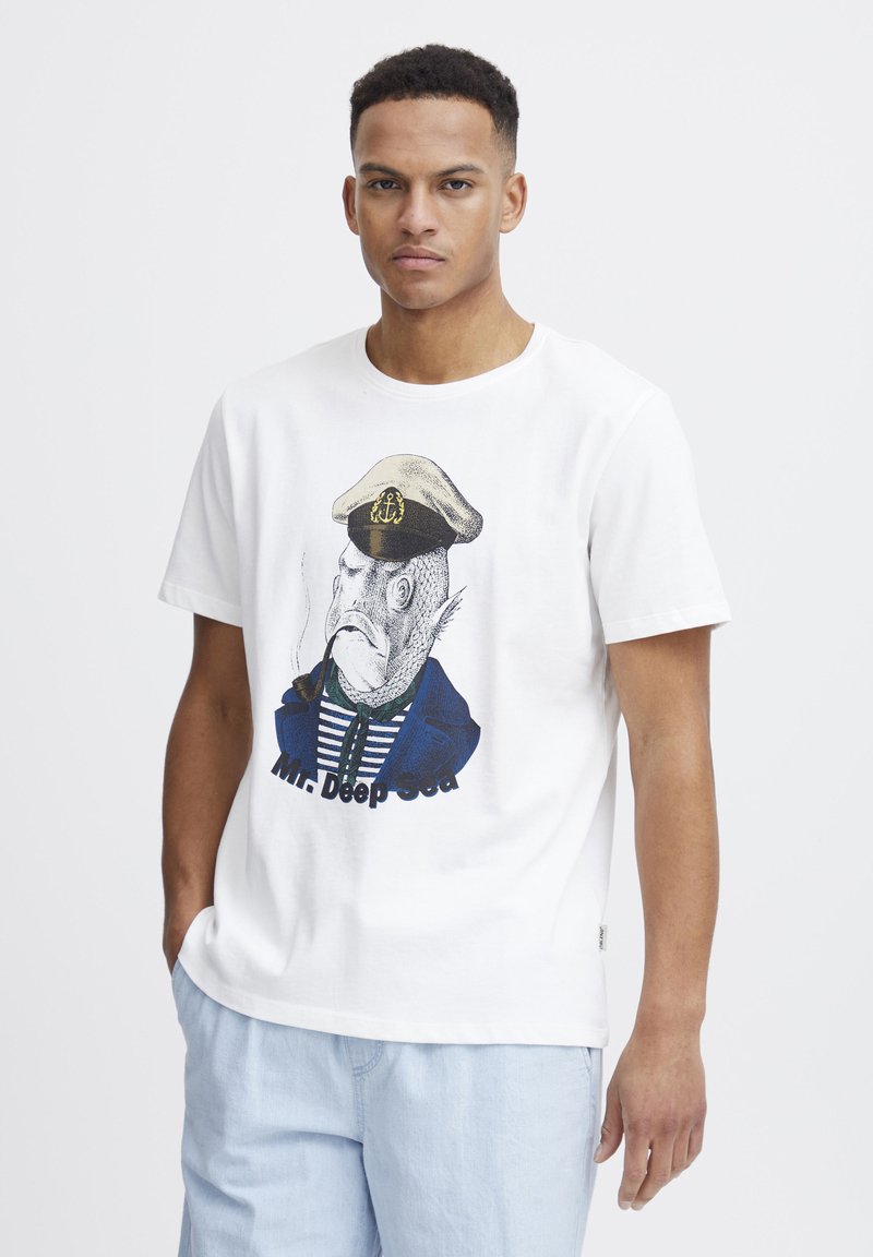 T-shirt bianco in cotone con un personaggio pesce che indossa un cappello da capitano, una camicia a righe e un cappotto blu, con "Mr. Deep Sea" stampato sotto.