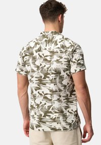 Chemise à manches courtes en tissu léger, dotée d'un motif abstrait texturé blanc et vert olive, avec un ourlet arrondi et un col rond.