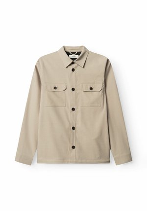 Béžová košeľa na gombíky s dlhým rukávom, dvoma vreckami s klopami na hrudi, tmavými gombíkmi a klasickým golierom, položená na plochu na bielom pozadí.