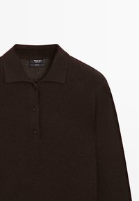 Braunwolliges Poloshirt mit langen Ärmeln und Kragen, dreiknöpfiger Knopfleiste, glatter Textur und minimalen Nähten, mit einem Markenetikett im Nacken.