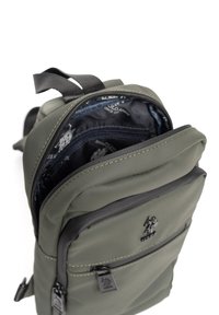 Zielony plecak nylonowy o teksturowanym wykończeniu, z podwójnym zapięciem na zamek i granatowym wnętrzem. Posiada małą przednią kieszeń oraz logo marki.