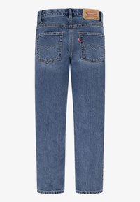 Jeans de mezclilla azul con un diseño de pierna recta, que cuentan con una parche de cuero marrón en la parte trasera de la cintura y dos bolsillos traseros con detalles de costura.