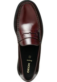 Mocassins en cuir marron avec une finition lisse, surpiqûres décoratives, un bout arrondi et une semelle en caoutchouc à motif. Présente la marque "GEOX" en doré.