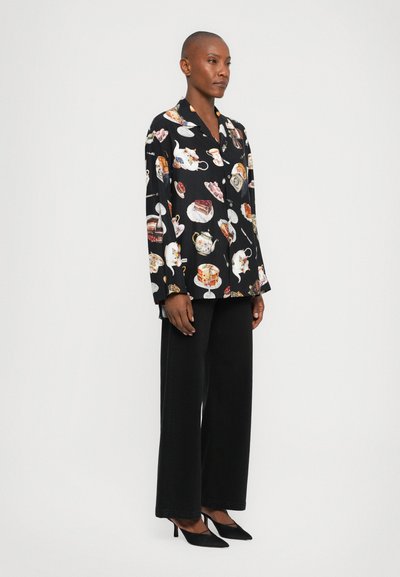 Black long-sleeve shirt with colorful tea and dessert motifs, paired with black wide-legged pants and black pointed heels.