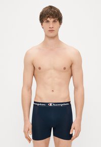 Boxer-briefs navy avec une ceinture élastique marquée. Fabriqués en tissu lisse, au design ajusté et dotés d'une poche anatomique pour un soutien optimal.