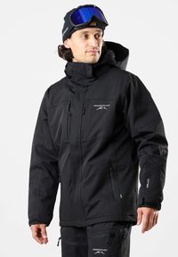 Schwarze Skijacke mit Kapuze, ausgestattet mit mehreren Reißverschlusstaschen, verstellbaren Bündchen und einem glatten, wasserfesten Stoff. Logo auf der Brust.