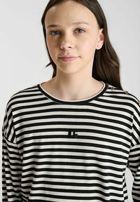 Zwart-wit gestreepte lange mouwen shirt met een ronde hals en zwarte logodetails. Heeft decoratieve knopen op de schouder.