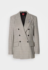 Δίπλο σακάκι με σχέδιο καρό σε τόνους μπεζ, μαύρου και μπλε. Διαθέτει αιχμηλούς γιακάδες, δύο εμπρόσθιες τσέπες και μαύρα κουμπιά.