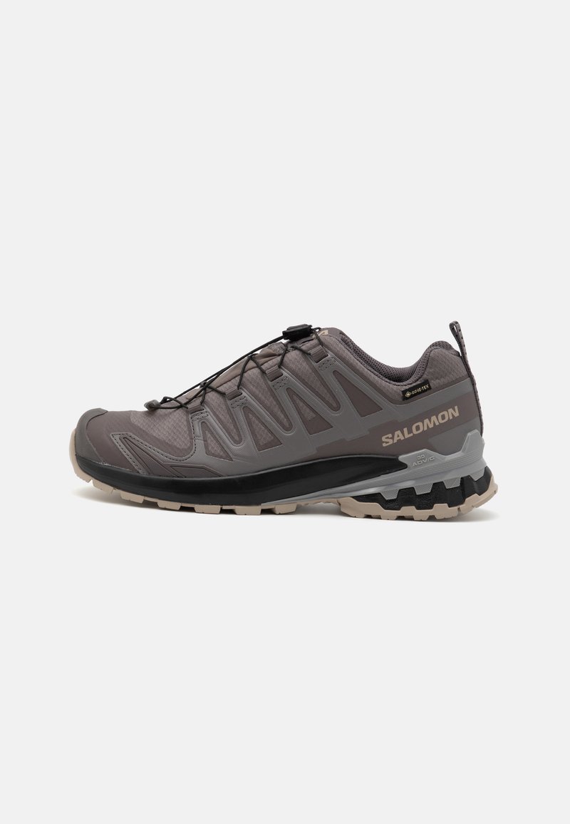 Gray outdoor shoe with a mesh and synthetic upper, a padded collar, and a textured sole featuring deep treads for traction. Adjustable lacing system.