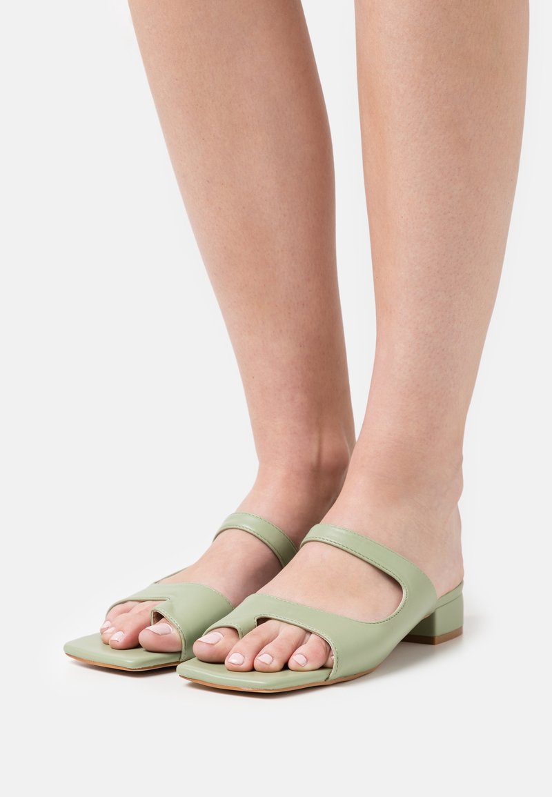 Sandali in pelle verde a scivolo con punta aperta, design quadrato e due cinturini sottili. Tacco basso e superficie liscia.