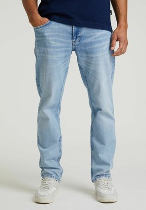 Light blue denim jeans with a straight fit, subtle fading, and front pockets, paired with white and grey sneakers on a neutral background.