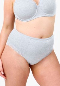 Harso puuvillane kõrge vöökohaga aluspüks, millel on laineline pitsäär, õmblusteta külgedega ning õmblused ees ja taga. Pehme tekstuur.