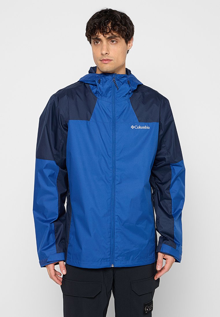 Veste imperméable bleue avec une capuche, comportant des accents bleu marine, une fermeture éclair et un logo sur la poitrine. Matériau léger et durable.
