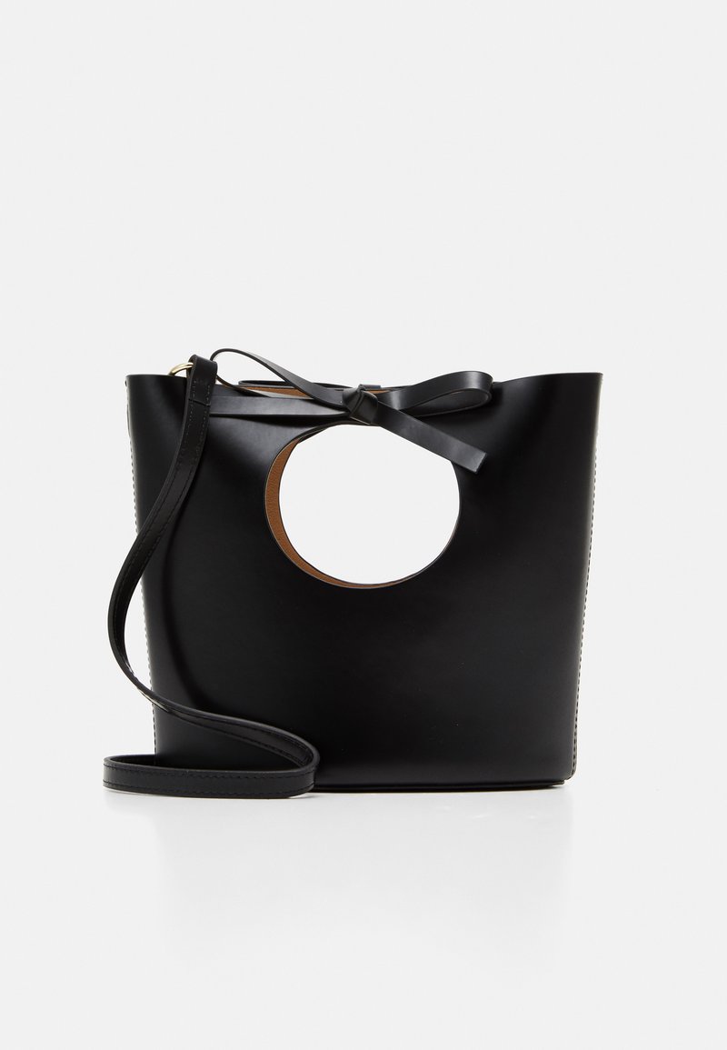 Μαύρη δερμάτινη τσάντα χειρός με κυκλικό κόψιμο, επίπεδο σχέδιο και λεπτομέρεια σε σχήμα φιόγκου. Διαθέτει λεπτό ρυθμιζόμενο λουρί ώμου.