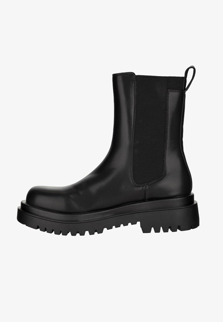 Czarny skórzany botek Chelsea z elastycznymi panelami po bokach, pętelką na pięcie oraz grubą, bieżnikowaną podeszwą zapewniającą przyczepność i trwałość.