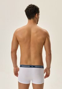 Białe bawełniane bokserki z granatowym pasem, na którym widnieje napis "HENDERSON". Krój jest dopasowany, podkreślając plecy i tors noszącego.