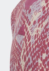 Texturovaný top Adidas s růžovým a bílým vzorem hadí kůže. Obsahuje růžovou nášivku s logem na hrudi a design s výstřihem do V.