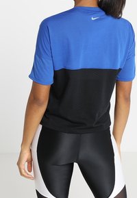Nike prestandatröja med blå övre del och svart nedre del med nättextur, korta ärmar och reflekterande logotypdetalj.