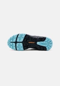 Schwarze Sneakersohle mit strukturiertem Design, das ein hellblaues Profilmuster und ein oranjes Logo-Detail aufweist, das Griffigkeit und Haltbarkeit betont.