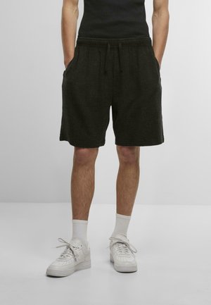 Sorte shorts i tekstureret stof med elastisk talje, sidelommer og en afslappet pasform, stylet med hvide sneakers og sokker.