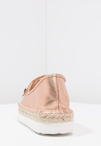 Scarpa espadrilla rose gold con finitura metallica, suola media in juta intrecciata e suola esterna in gomma bianca. Presenta un dettaglio a fiocco di lato.