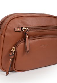 Borsa a tracolla in pelle marrone con due scomparti con zip, accessori in metallo dorato e una finitura liscia e texturizzata. Logo del brand impresso.